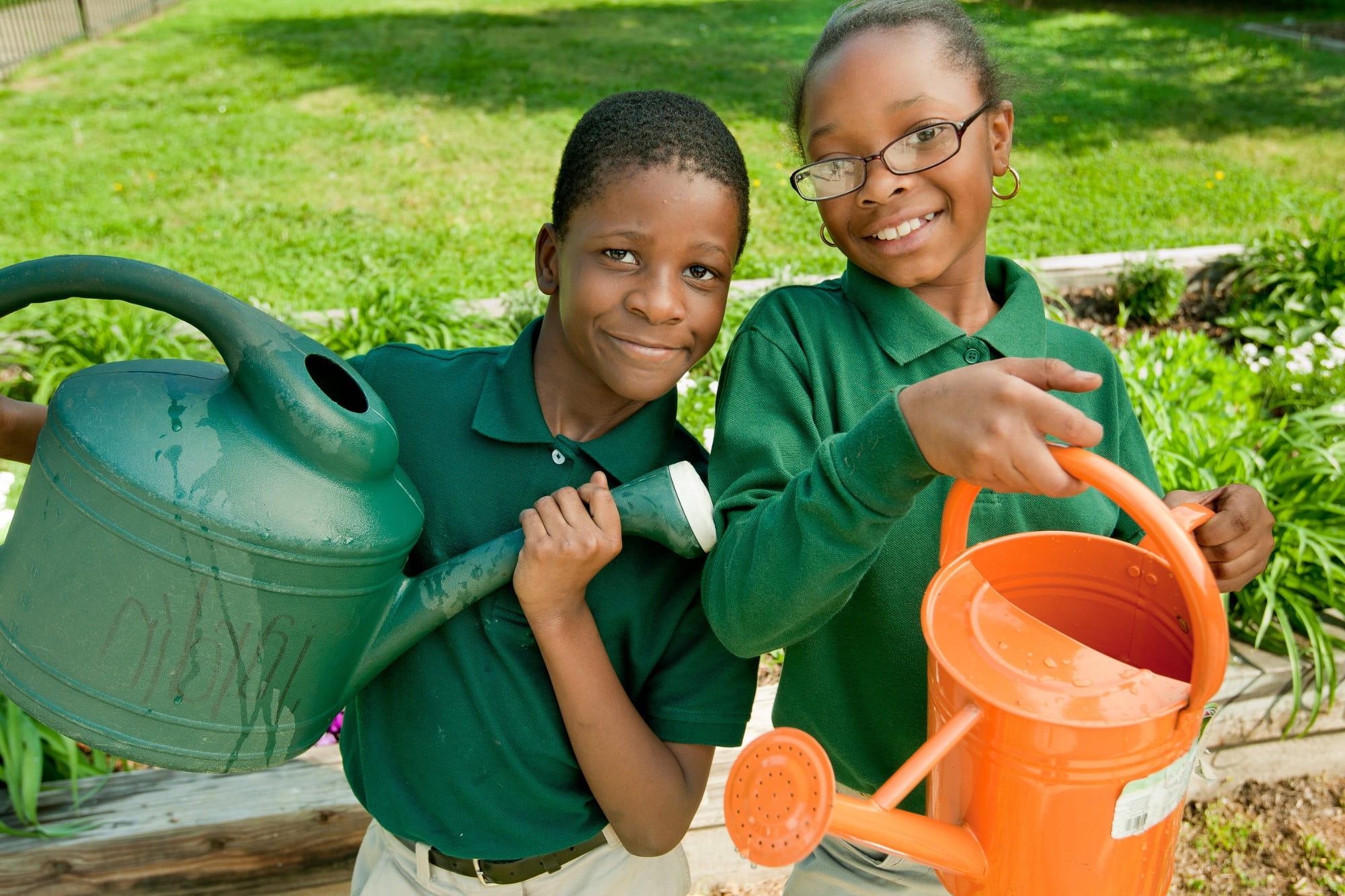 两个学生拿着水壶参加学校的园艺活动