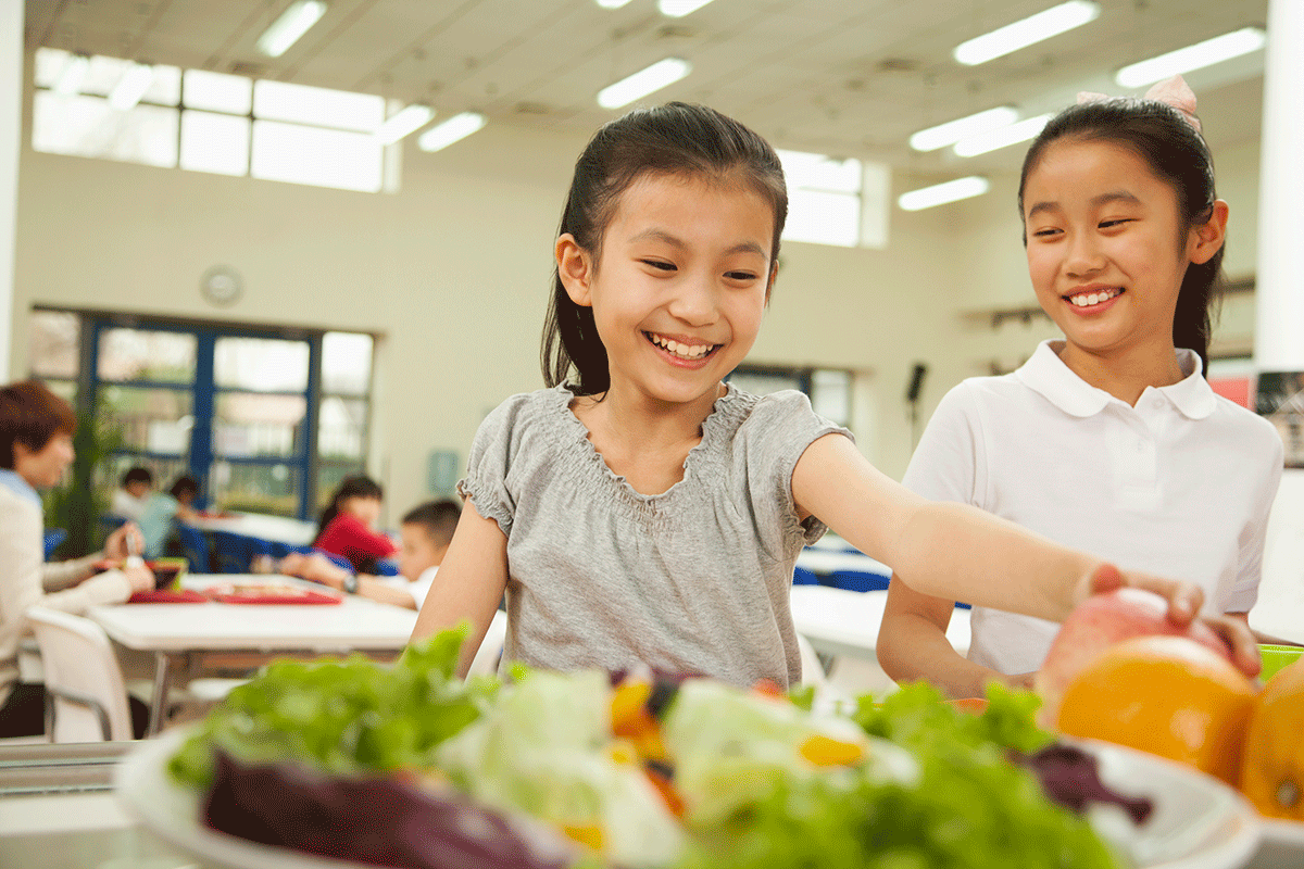 快乐的小学生在学校午餐队伍中选择食物