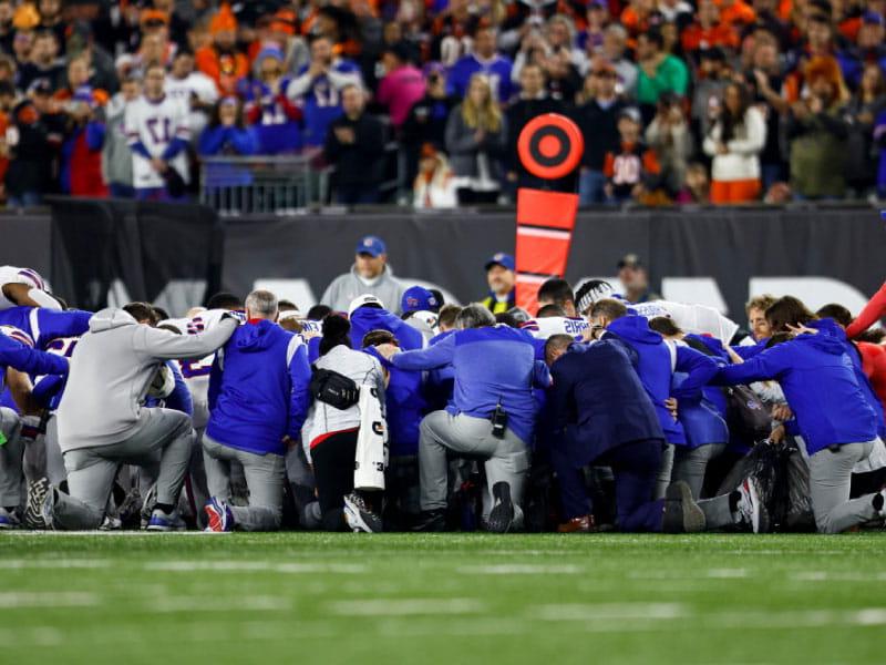 Buffalo Bills players and staff kneel after Damar Hamlin collapsed during an NFL football game against the Cincinnati Bengals on Jan. 2, 2023 in Cincinnati. (Kevin Sabitus/Getty Images)