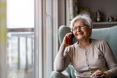 older woman sitting in chair at home talking on the phone